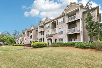 Apartment building with balconies and green lawn in front.